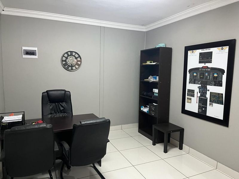 A functional commercial office space featuring neutral grey walls, crown molding, and clean tiled flooring, suitable for professional use.