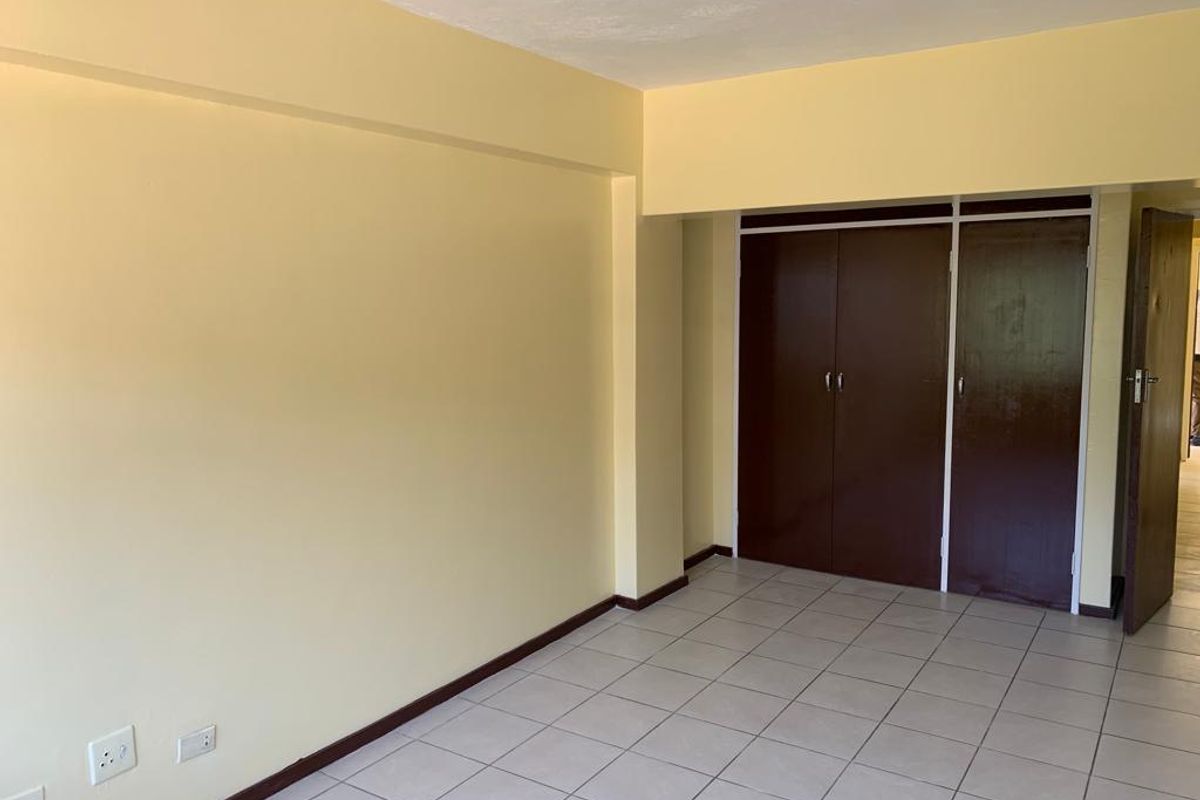 An empty bedroom featuring tiled flooring and built-in cupboards, offering a blank canvas for personalization and interior design updates.