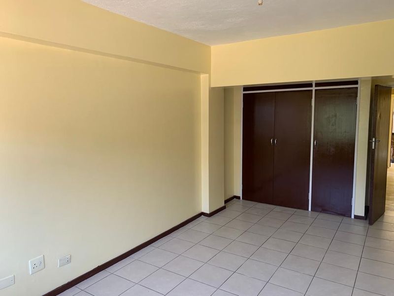 An empty bedroom featuring tiled flooring and built-in cupboards, offering a blank canvas for personalization and interior design updates.