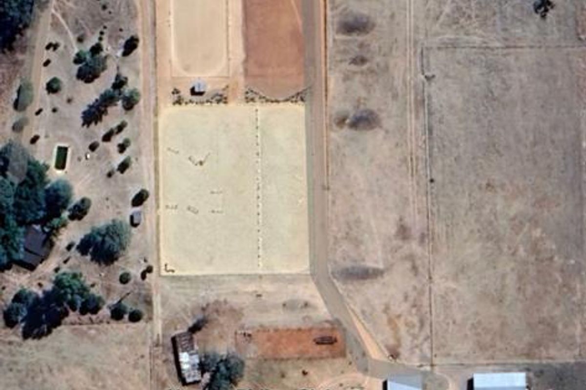 Aerial view of the equestrian facility featuring multiple riding arenas, stables, and a lunging ring on a large farm property.