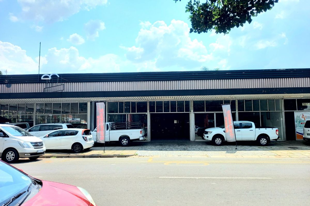 Front elevation of a commercial property featuring a large glass storefront and paved frontage, suitable for retail or showroom use.