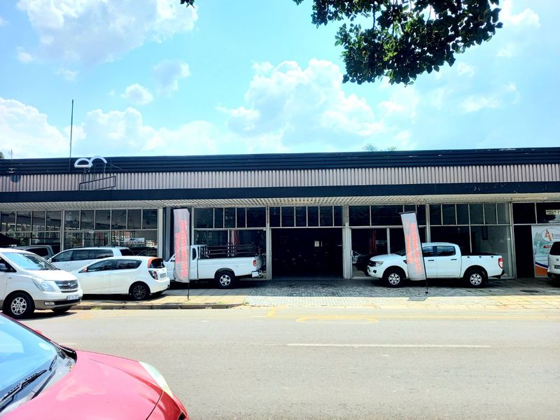 Front elevation of a commercial property featuring a large glass storefront and paved frontage, suitable for retail or showroom use.