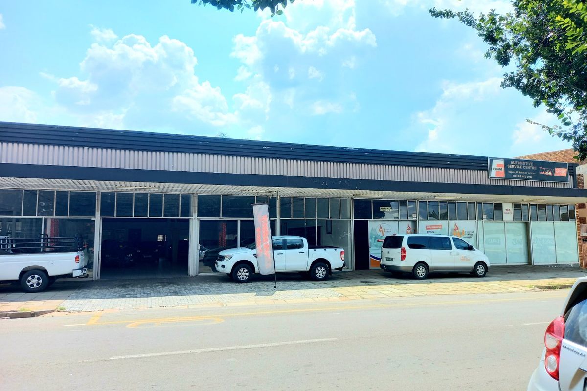 Commercial automotive service centre featuring a large glass storefront, metal roof, and paved frontage with direct street access.