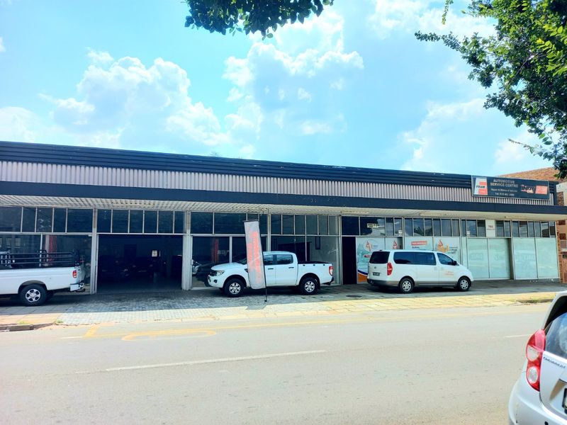 Commercial automotive service centre featuring a large glass storefront, metal roof, and paved frontage with direct street access.