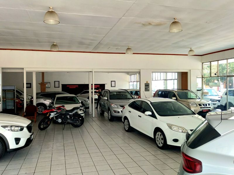 Spacious commercial showroom featuring tiled flooring, suspended ceilings with pendant lighting, and large glass windows providing ample natural light.