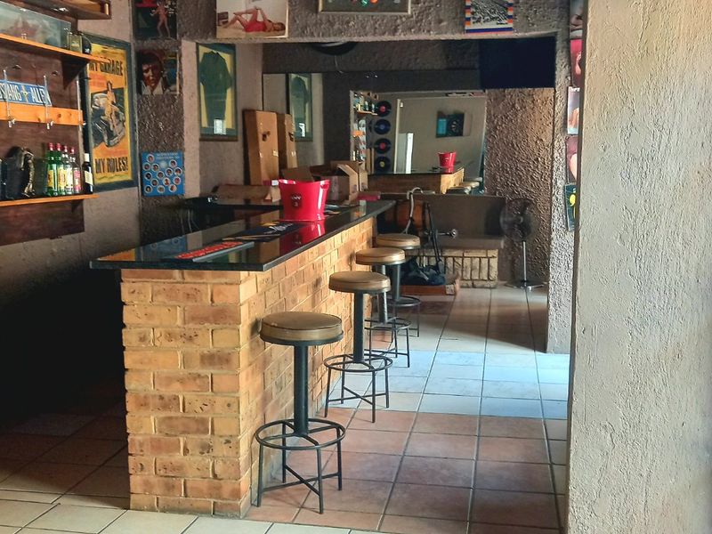 A dedicated bar area featuring a built-in brick counter with a granite top and tiled flooring, suitable for commercial entertainment or hospitality use.