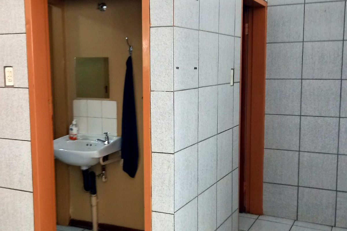 Commercial bathroom facility featuring tiled walls and flooring with multiple partitioned cubicles and wall-mounted basins.