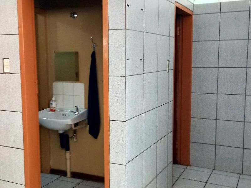 Commercial bathroom facility featuring tiled walls and flooring with multiple partitioned cubicles and wall-mounted basins.