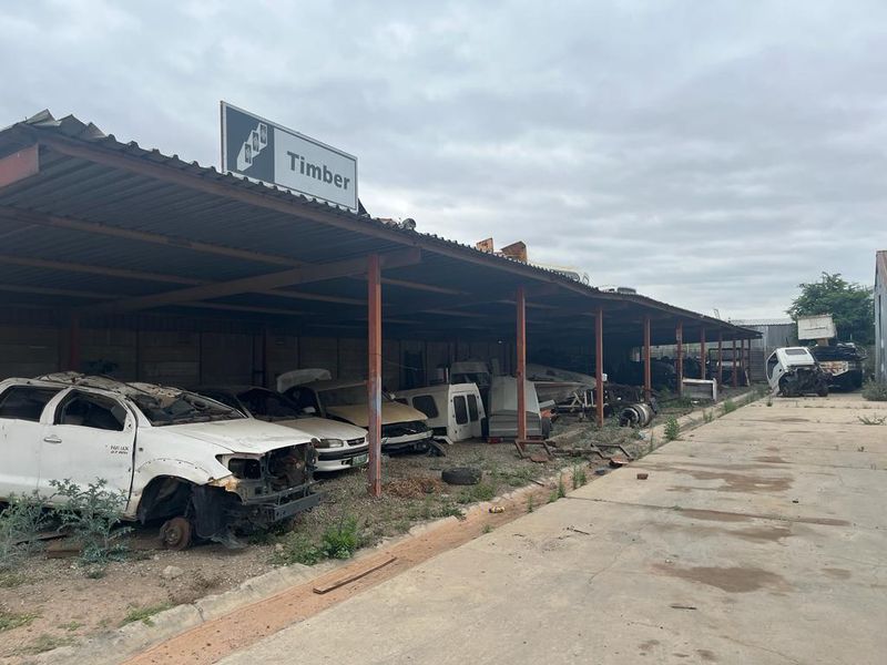 Commercial outdoor storage area featuring a large covered structure with steel supports and concrete flooring, suitable for industrial or yard use.
