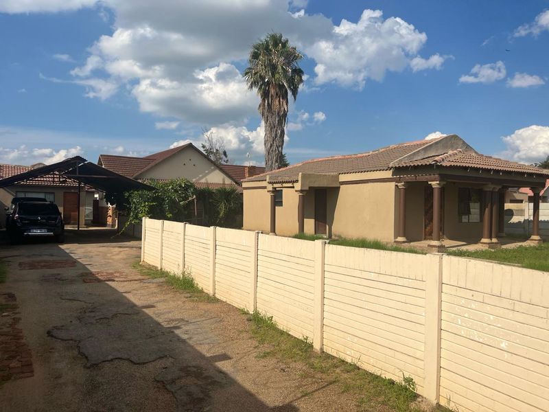 Front view of a residential property featuring a tiled roof, covered porch with columns, a concrete driveway, and a precast concrete boundary wall.