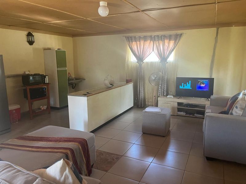 Open plan living area featuring tiled flooring and a basic kitchenette counter, requiring cosmetic updates to improve the overall aesthetic and condition.