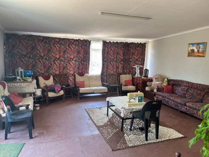 A spacious living room featuring a simple ceiling light and basic flooring, offering a blank canvas for potential renovation and modern interior updates.