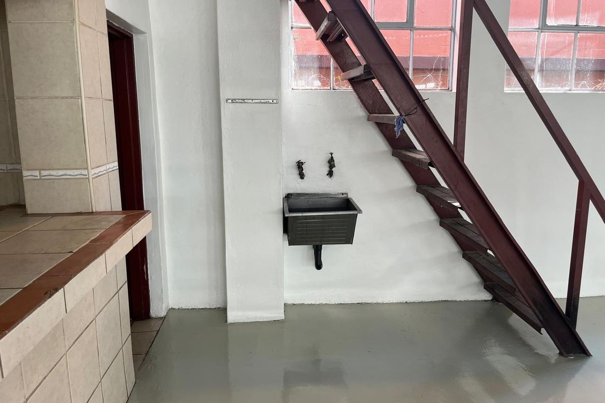 Utility area featuring a wall-mounted sink, tiled counter space, and a metal staircase leading to an upper level.