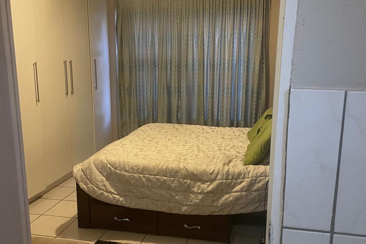 A bedroom featuring built-in cupboards and tiled flooring, viewed from the doorway.