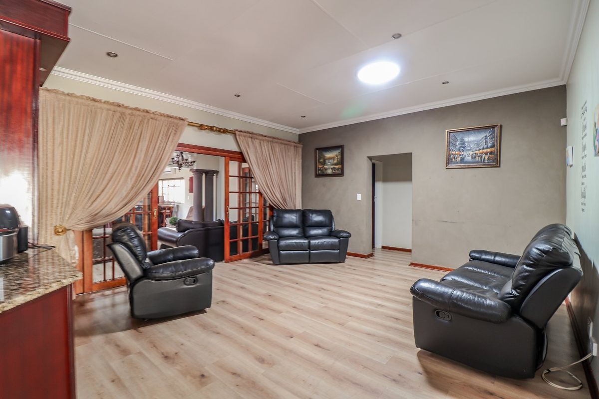 Spacious living area featuring light wood-look laminate flooring, recessed ceiling lighting, and a large sliding door leading to an adjacent room.