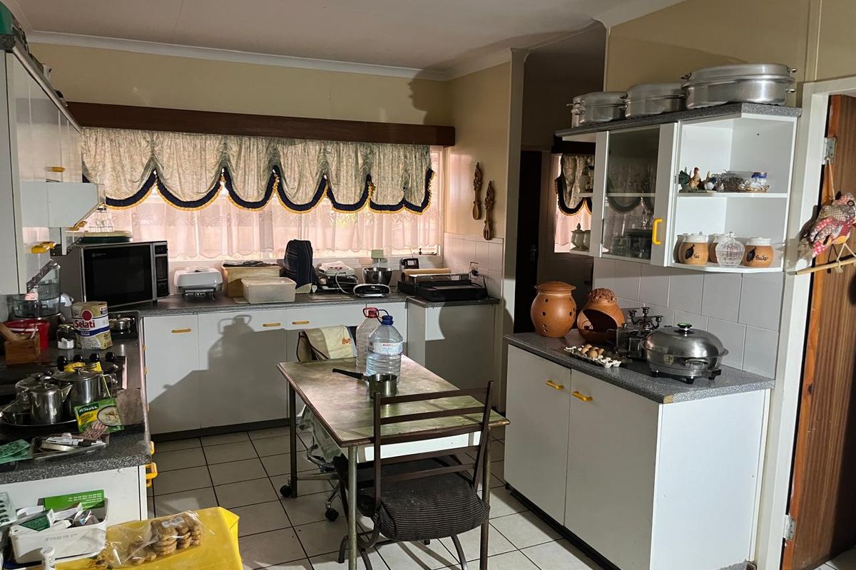 A functional kitchen featuring tiled flooring, laminate countertops, and ample built-in cabinetry, offering a dated aesthetic ready for modernization.