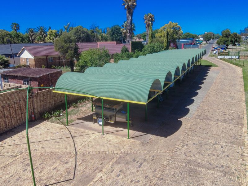 Aerial view of a commercial property featuring an extensive covered parking area with corrugated metal roofing and paved driveway access.
