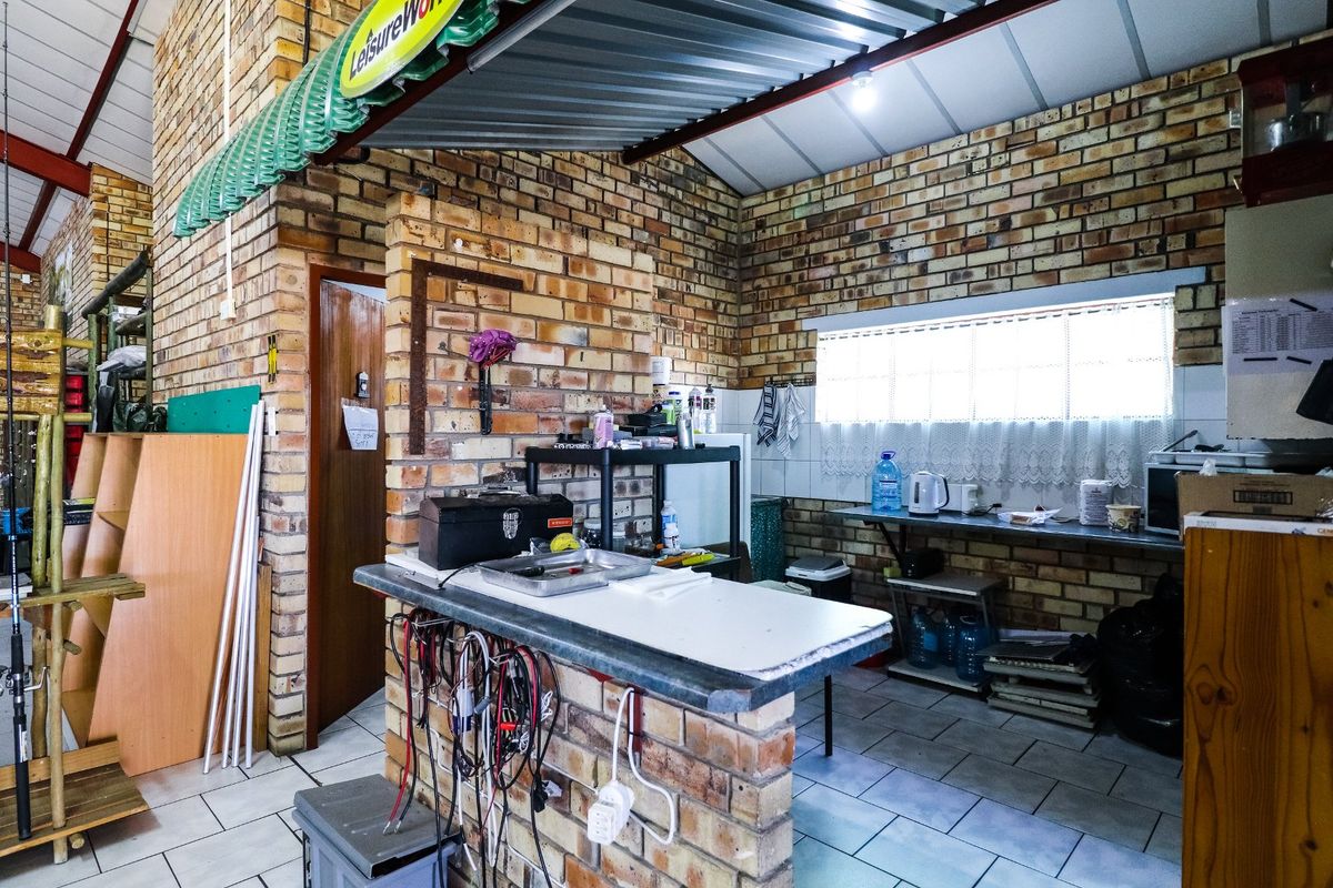 A rustic commercial kitchen area featuring exposed brick walls, tiled flooring, and a built-in brick counter with integrated workspace.