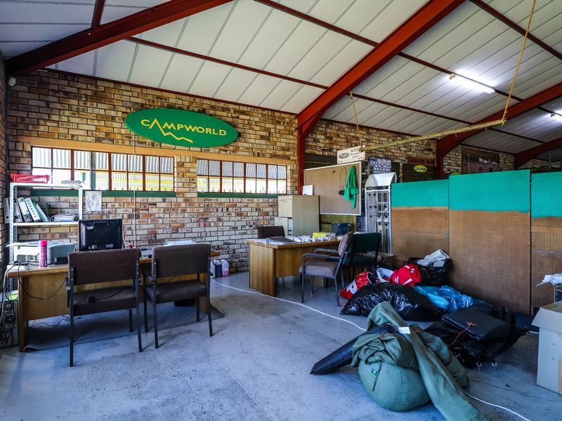 Commercial office space featuring exposed brick walls, steel roof trusses, and concrete flooring, currently utilized as a functional workspace.