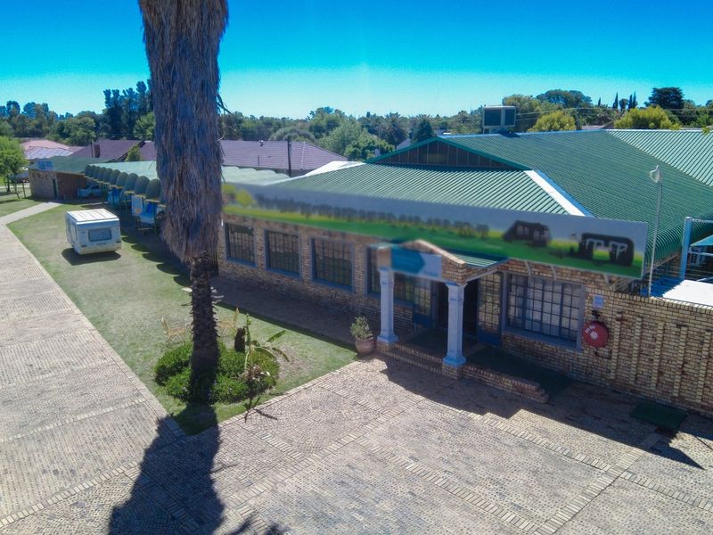Aerial view of a commercial property featuring a brick facade, corrugated metal roofing, and extensive paved driveway areas.