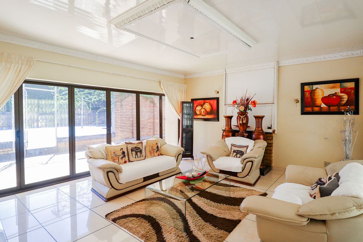 Spacious living room featuring large sliding glass doors, polished tile flooring, and decorative ceiling detailing, offering a bright and open atmosphere.