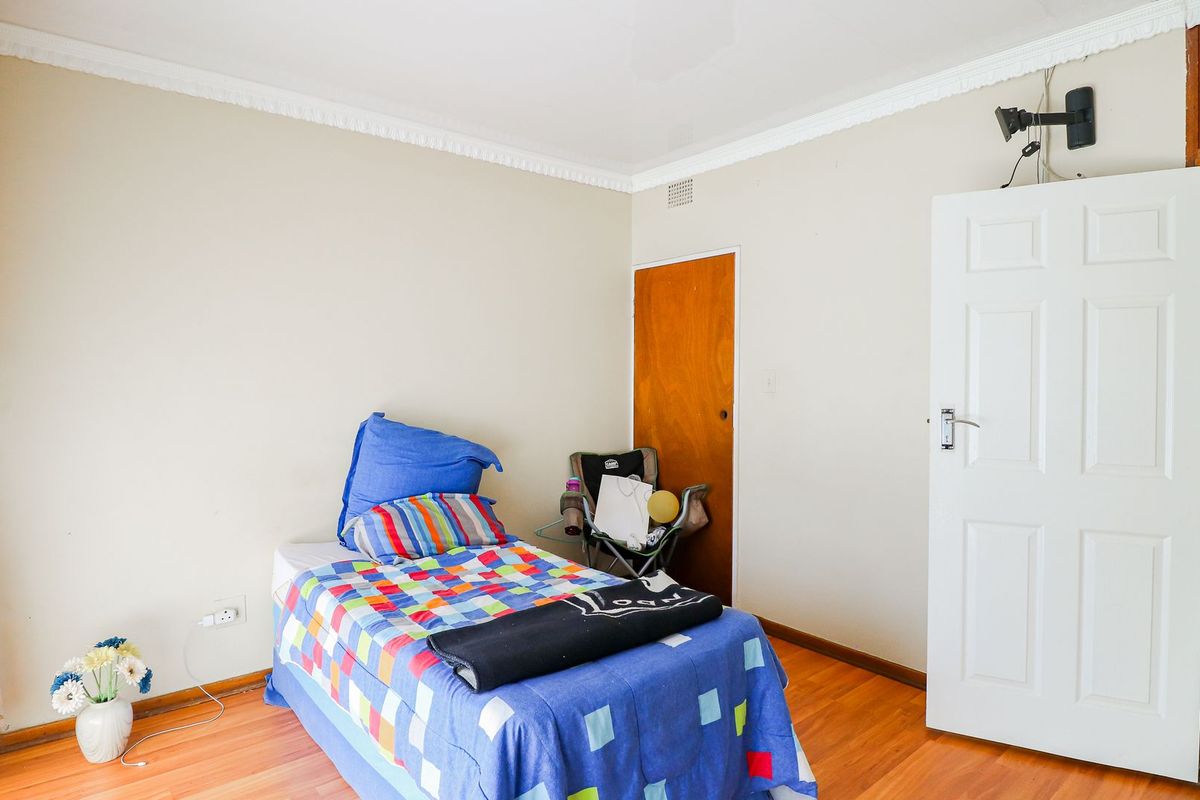 A bedroom featuring laminate flooring, crown molding, and a built-in cupboard, providing a functional space with neutral wall finishes.
