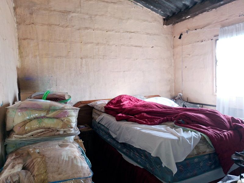 A bedroom featuring exposed masonry walls and timber rafters, requiring significant renovation and surface finishing to improve the overall condition and aesthetic appeal.
