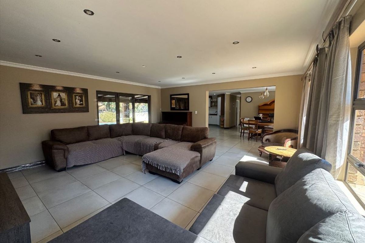 Spacious open-plan living area featuring neutral tiled flooring, recessed lighting, and large sliding doors providing natural light and access to the exterior.