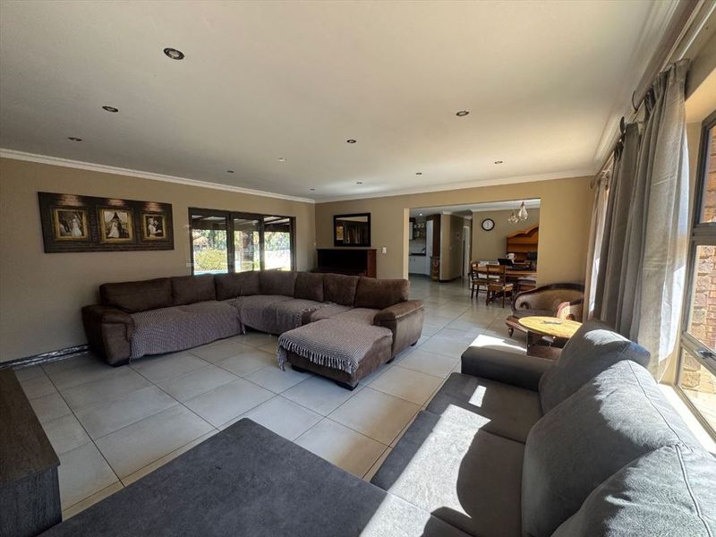 Spacious open-plan living area featuring neutral tiled flooring, recessed lighting, and large sliding doors providing natural light and access to the exterior.