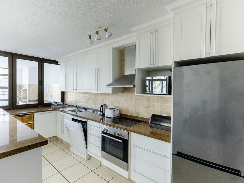 A well-maintained kitchen featuring white shaker-style cabinetry, granite countertops, a built-in oven, electric hob, and a tiled backsplash.