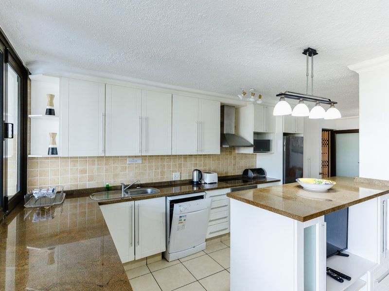 A functional kitchen featuring white cabinetry, granite countertops, a central island, and a tiled backsplash, offering a clean and practical workspace.