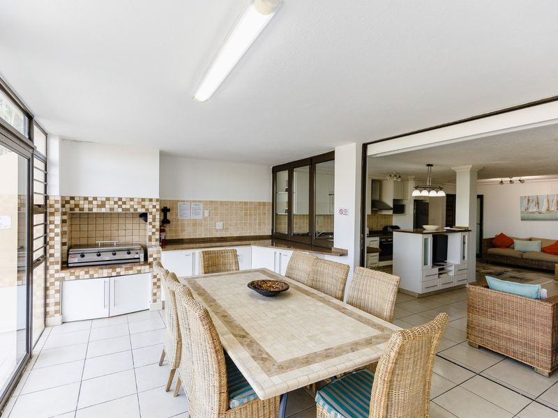 Covered patio area featuring a built-in braai, tiled flooring, and direct access to the open-plan living space through large sliding doors.