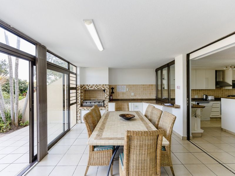 Enclosed patio area featuring a built-in braai, tiled flooring, and large sliding glass doors providing access to the outdoor space.