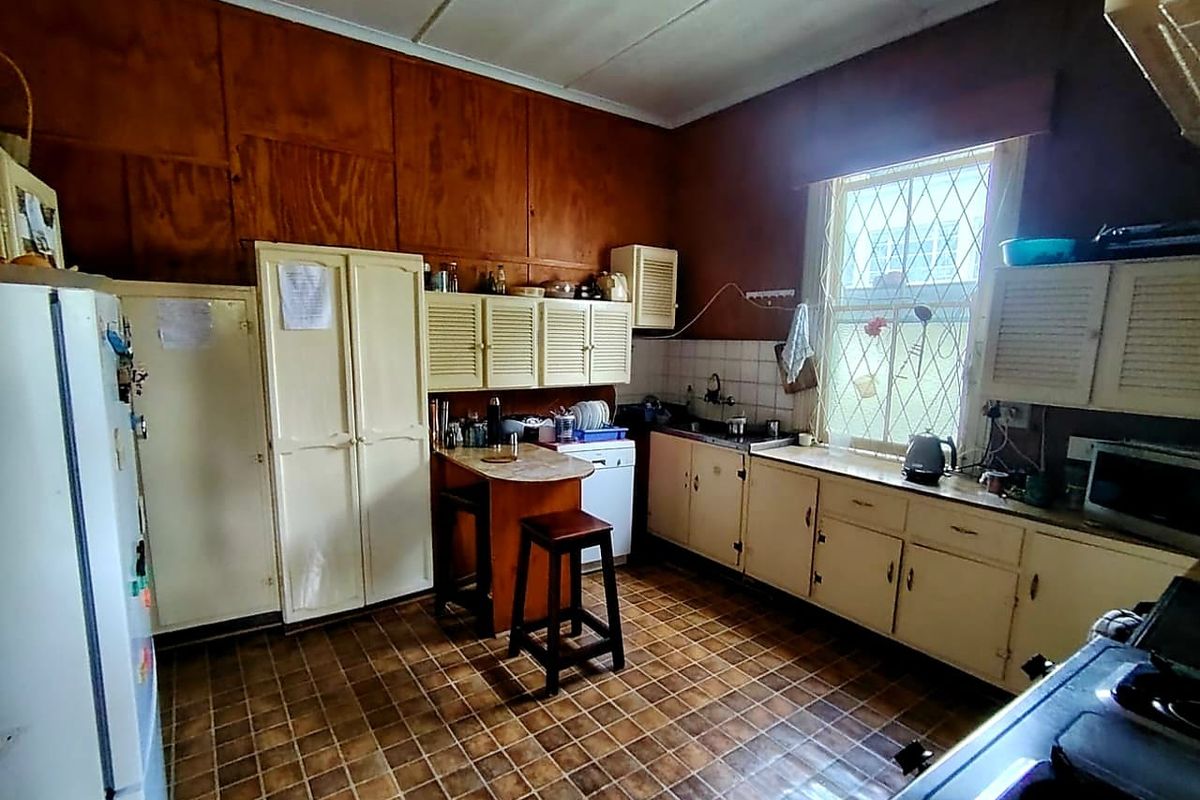 A dated kitchen featuring original cabinetry, tiled flooring, and wood-paneled walls, offering significant potential for a modern renovation and layout update.