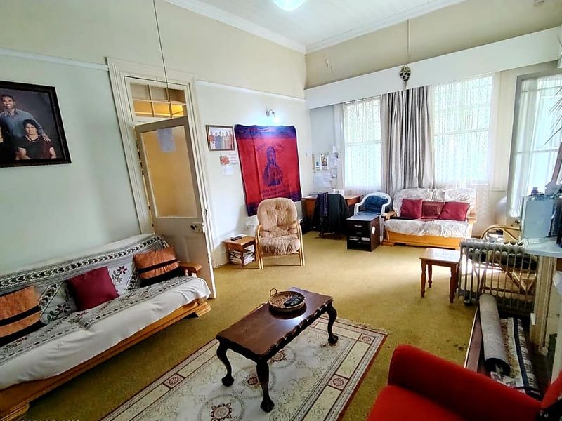 A spacious living room featuring high ceilings, traditional picture rails, and large windows that provide ample natural light.