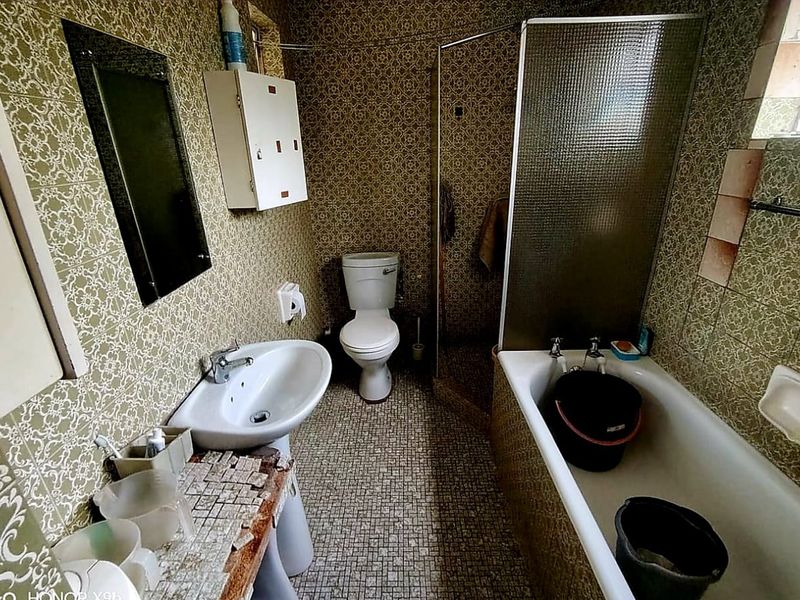 A dated bathroom featuring a pedestal sink, toilet, bathtub, and separate shower enclosure with original patterned wall tiles.