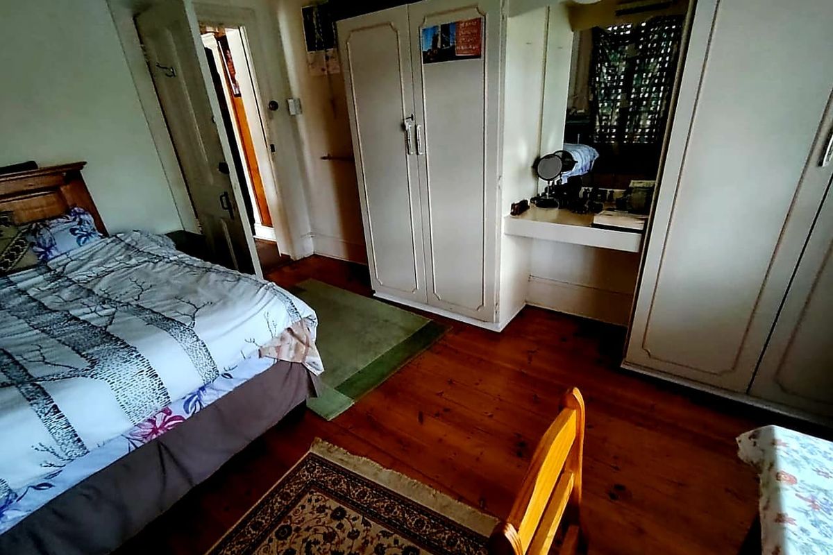 A bedroom featuring timber flooring and built-in wardrobe cabinetry with an integrated vanity area.