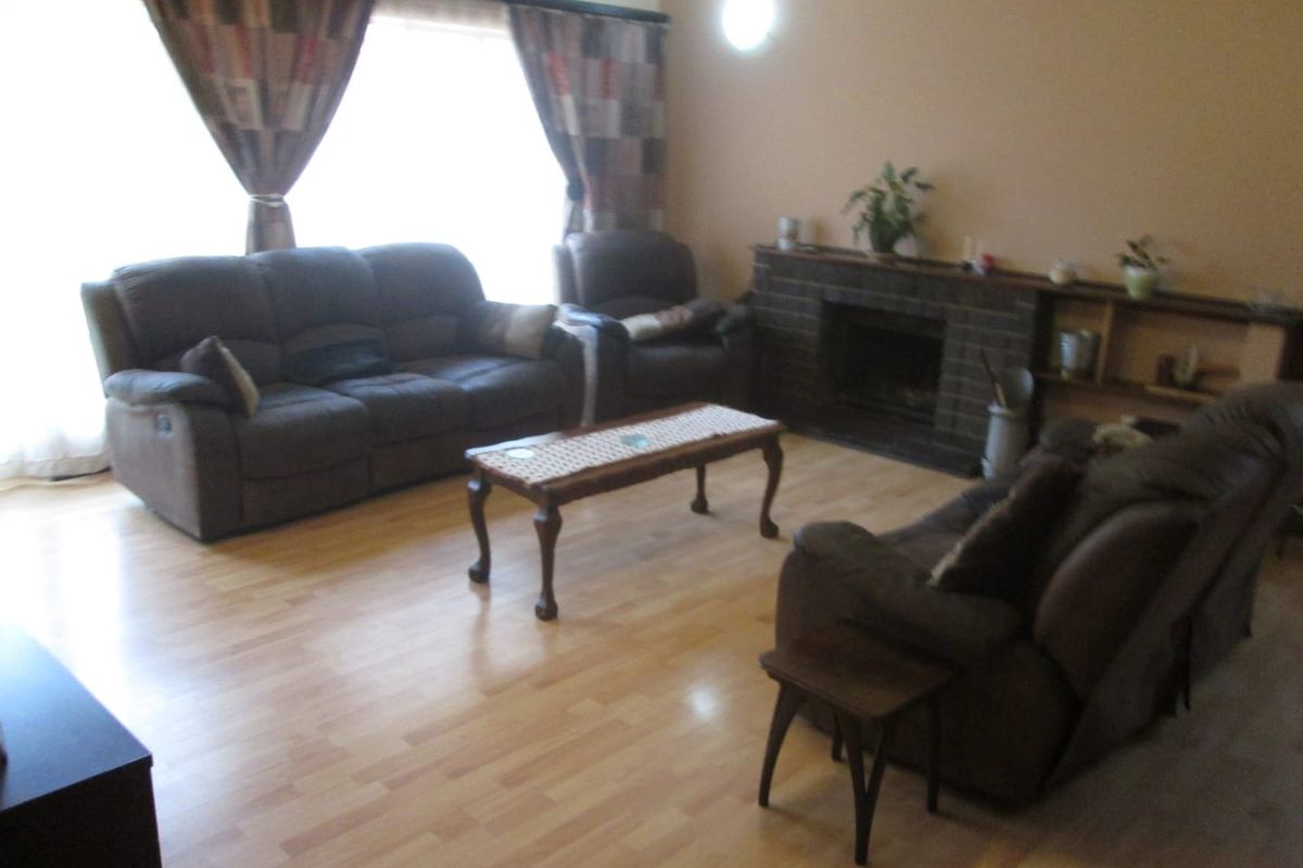 A living room featuring laminate flooring and a brick fireplace with integrated shelving, offering a functional and comfortable space.