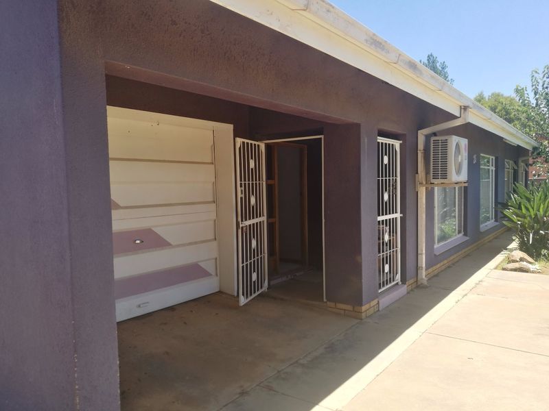 Front exterior view of the house featuring a garage, security gates, and an external air conditioning unit.