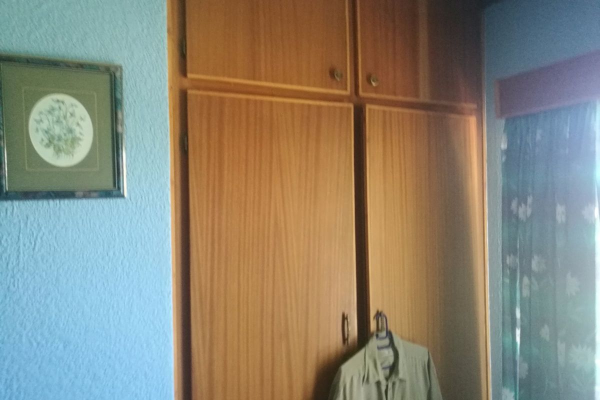 A bedroom featuring a full-height built-in wooden wardrobe with overhead storage compartments.