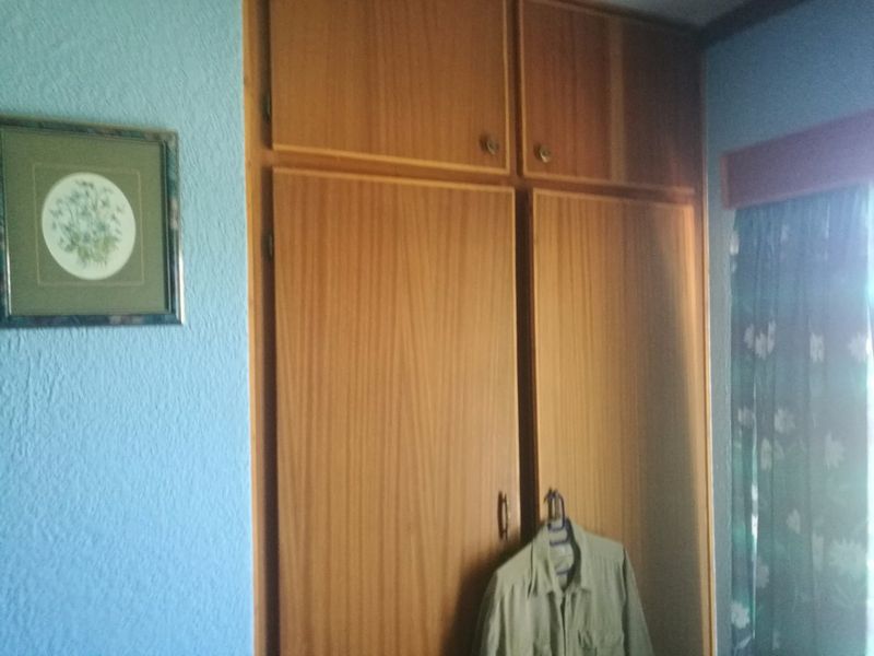 A bedroom featuring a full-height built-in wooden wardrobe with overhead storage compartments.