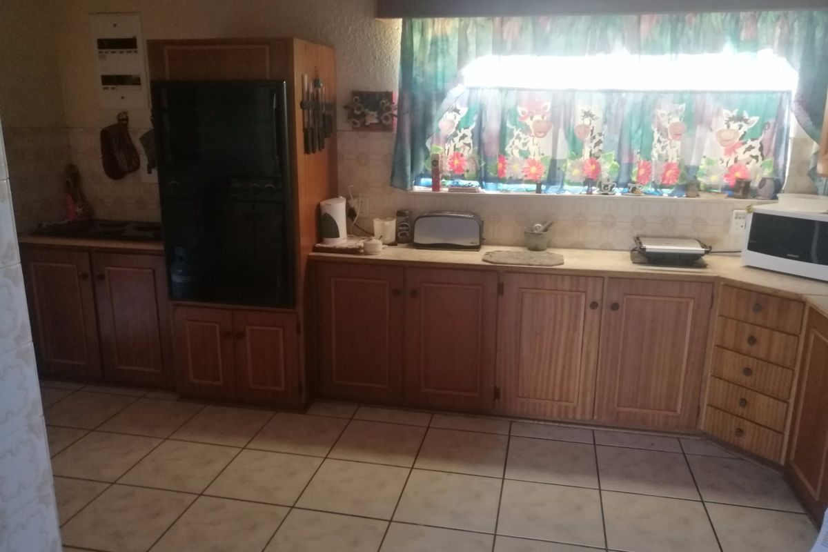 A dated kitchen featuring wooden cabinetry, tiled flooring, and a tiled backsplash, offering a functional layout with potential for modern renovation.