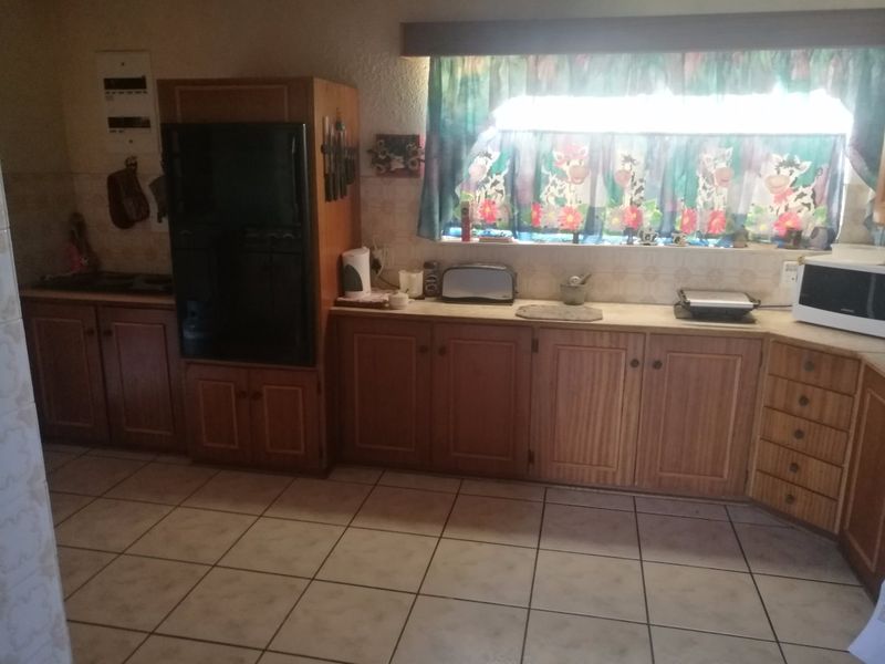 A dated kitchen featuring wooden cabinetry, tiled flooring, and a tiled backsplash, offering a functional layout with potential for modern renovation.
