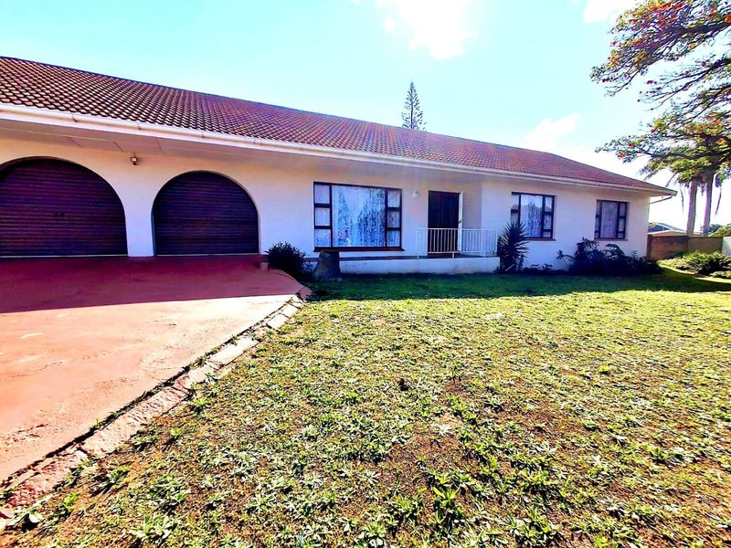 Front elevation of a single-story house featuring a tiled roof, double garage with arched doors, and a paved driveway.
