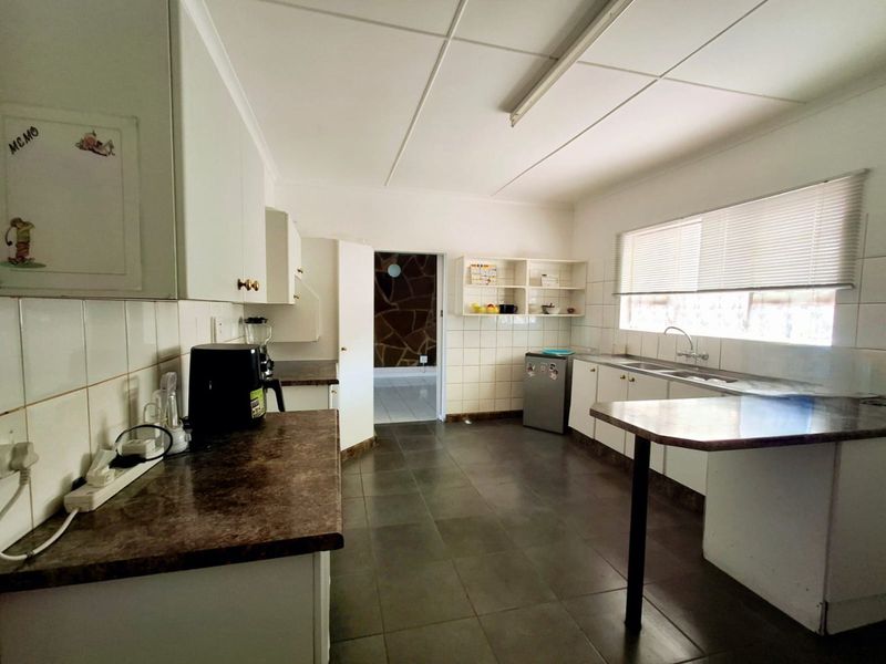 A functional kitchen featuring laminate countertops, built-in cabinetry, a double basin sink, and a breakfast bar, offering potential for modern renovation.