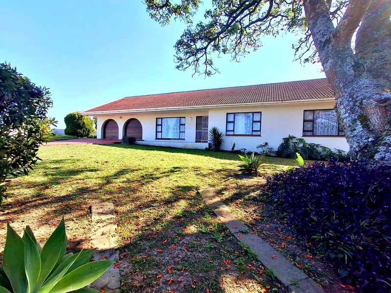 Front view of a single-story residential house featuring a tiled roof, arched garage doors, and established garden surroundings.