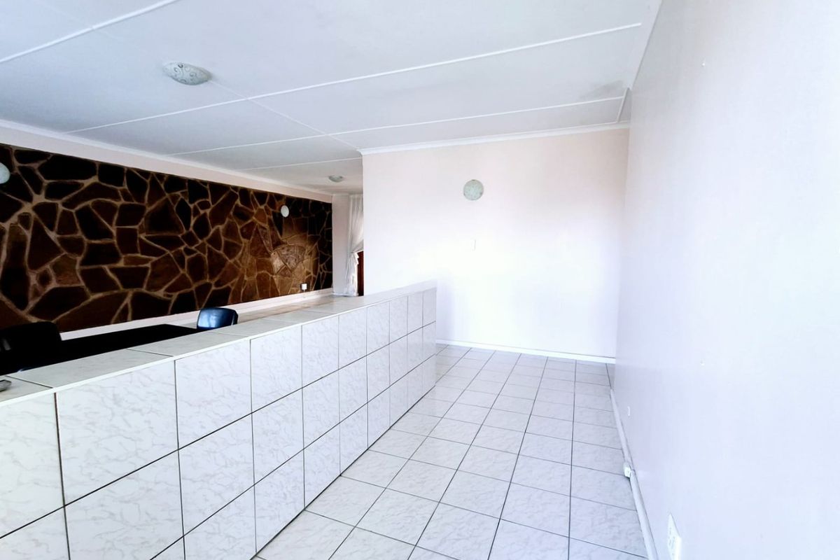An empty living area featuring tiled flooring, a stone accent wall, and a built-in counter, offering a blank canvas for interior design.