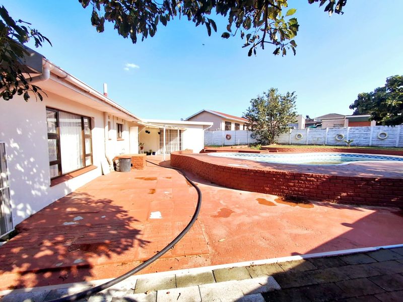 Outdoor entertainment area featuring a swimming pool with a brick surround and a paved patio space, ideal for renovation and landscaping updates.