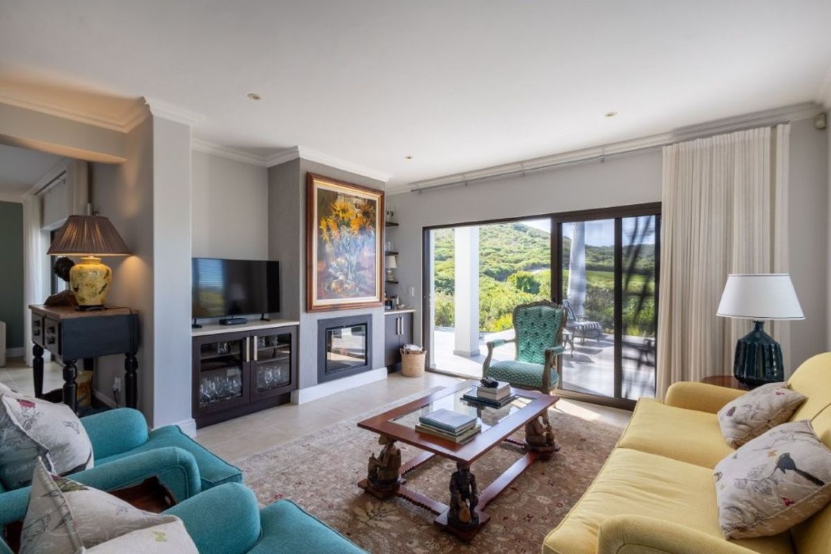 A bright and inviting living room featuring a built-in fireplace, custom cabinetry, and large sliding glass doors that open to a scenic outdoor patio.