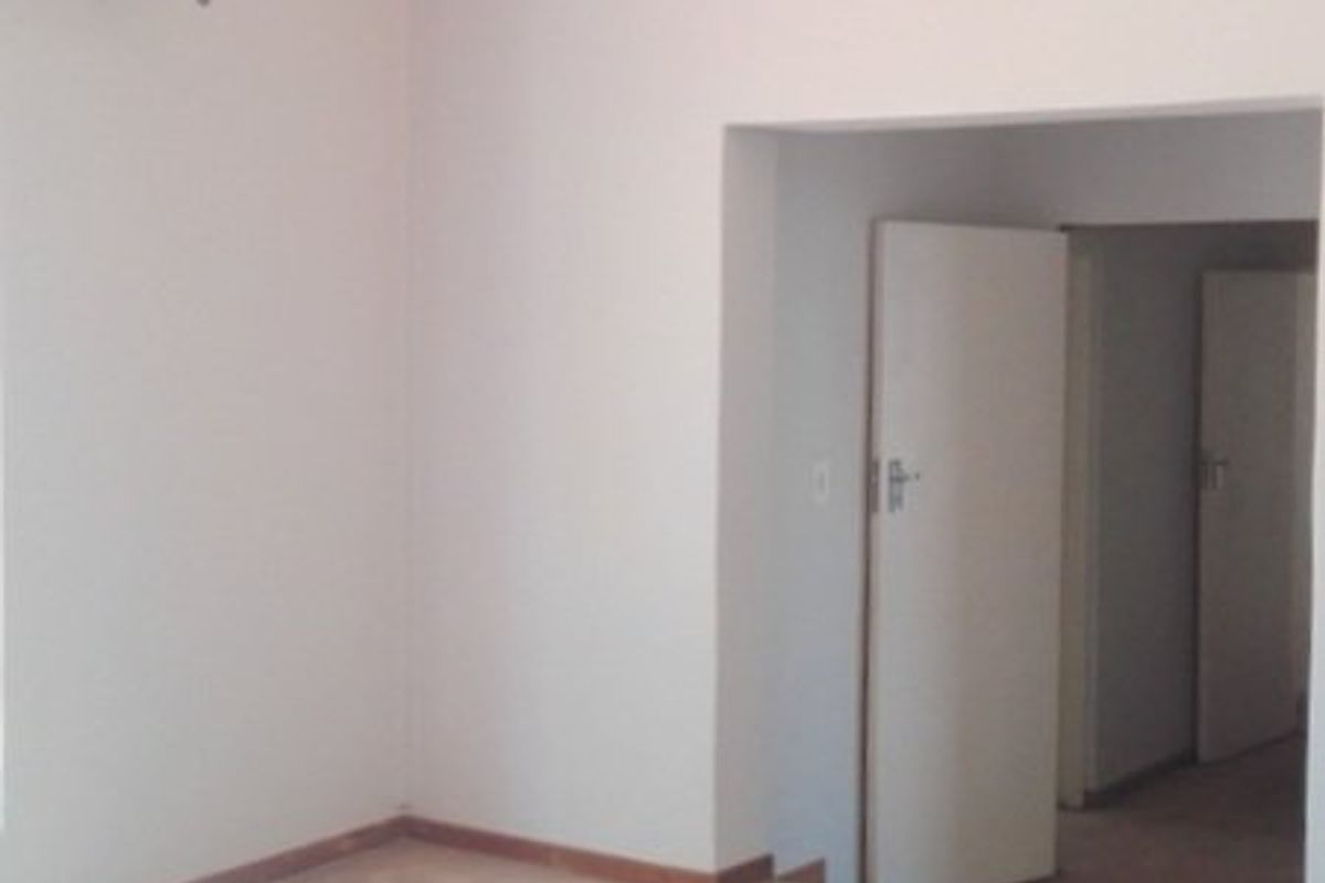 An empty bedroom featuring a high vaulted ceiling with exposed timber beams and neutral carpeted flooring.